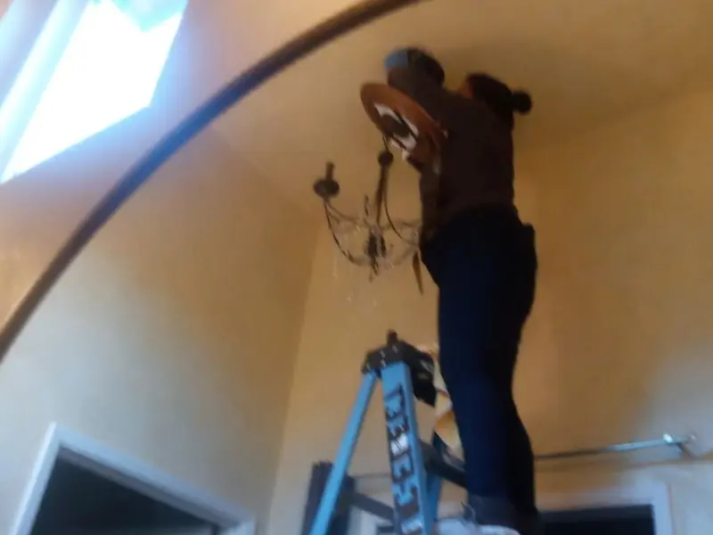Electrician installing a chandelier in a Deerfield residence
